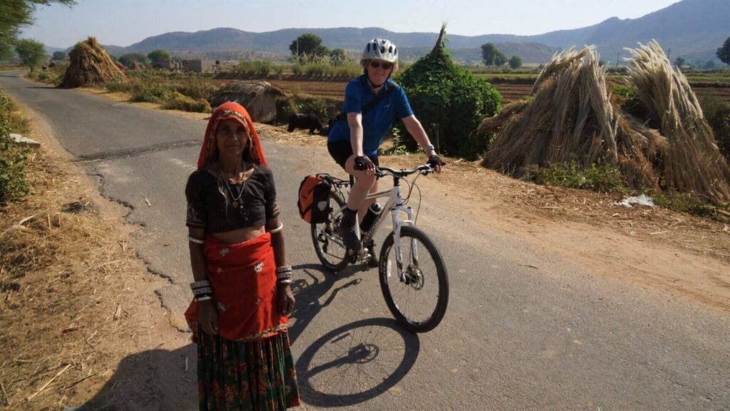 Rajasthani village women and a woman on a bicycle on a rural road. Khejarla, Rajasthan, India