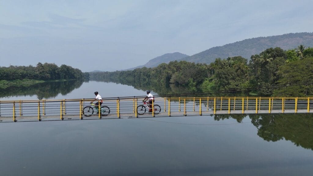 Cycling across a hanging bridge in Thattekad, Kerala, over the Periyar River, leading to local villages for a day of sightseeing and cultural immersion.