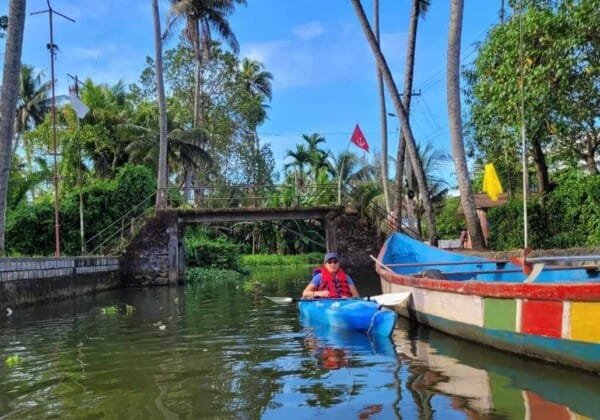 Kayakers paddling through the tranquil backwaters of Alleppey, Kerala, surrounded by palm-fringed canals and picturesque village scenery.
