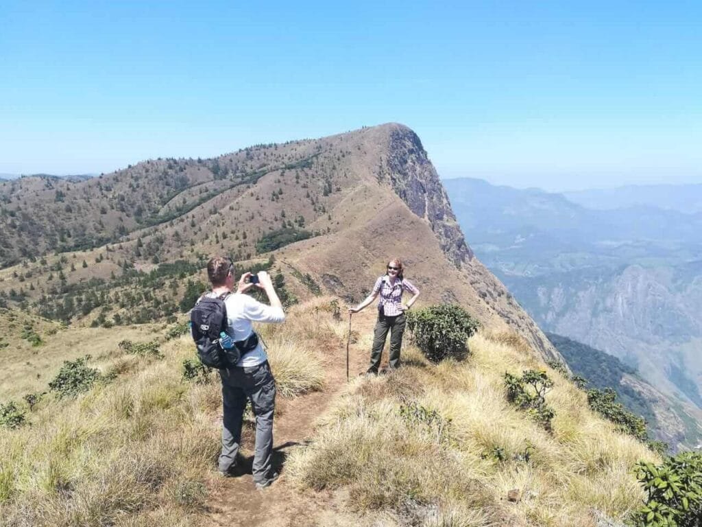 The Meeshapulimala trek in Kerala, showcasing trekkers ascending through mist-covered hills and verdant landscapes, with breathtaking views of the Western Ghats.