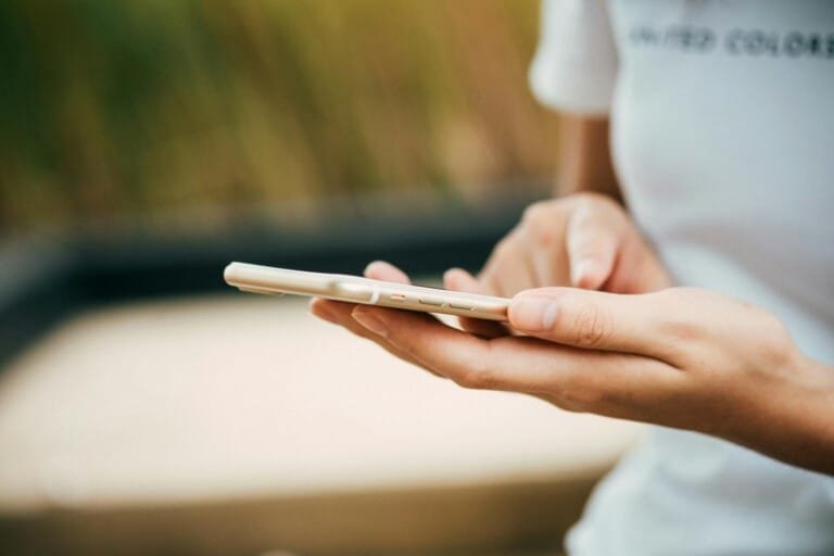 A person holding a cell phone against a plain white background.