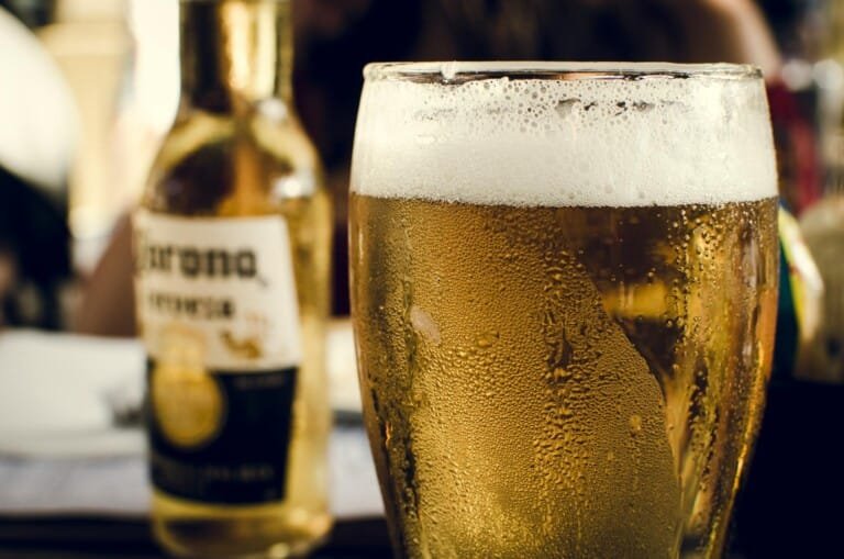 A chilled glass of beer on a table, showcasing its golden color and frothy top.